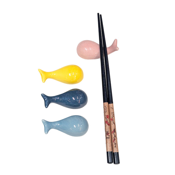 Ceramic whale chopstick rests in pink, yellow, dark blue, and light blue with one pair of chopsticks