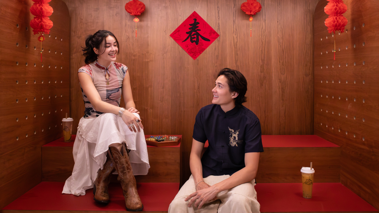 Woman and man chatting in a space with a Chinese character sign behind them